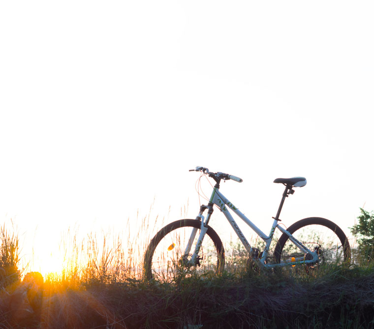 Umweltfreundlich mit dem Fahrrad auf einem Feldweg vor Sonnenaufgang