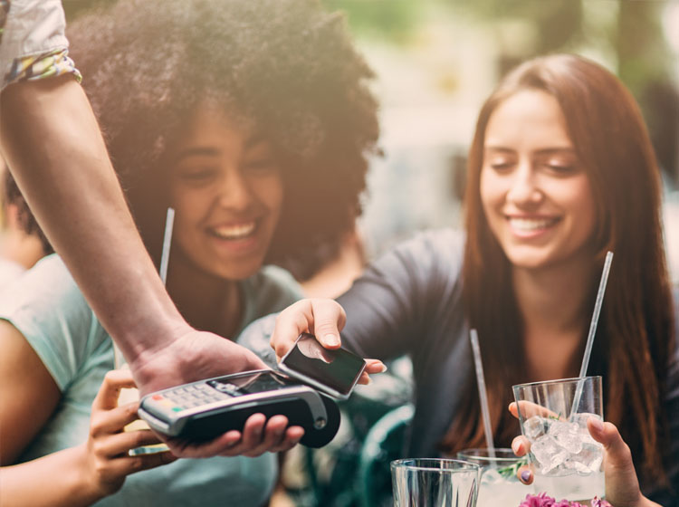 Freundinnen bezahlen Getränke mit Google Pay auf dem Handy