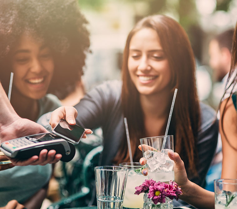 Junge Frau bezahlt mit ihrem Mobiltelefon und der A1 Mastercard App