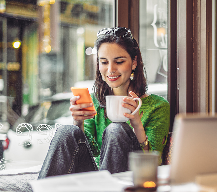 Junge Frau sitzt mit Handy im Café